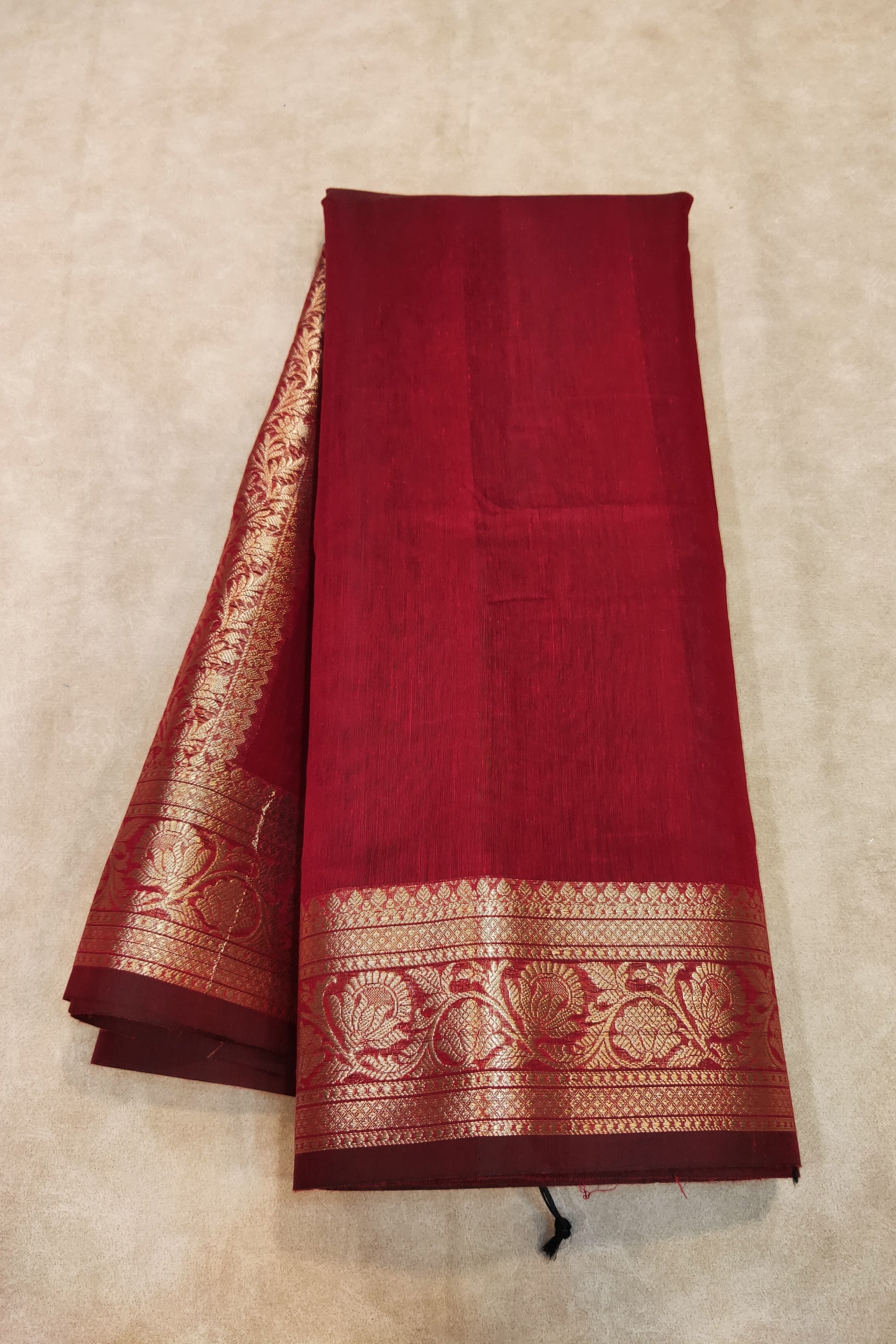 Red saree with gold border on a beige background