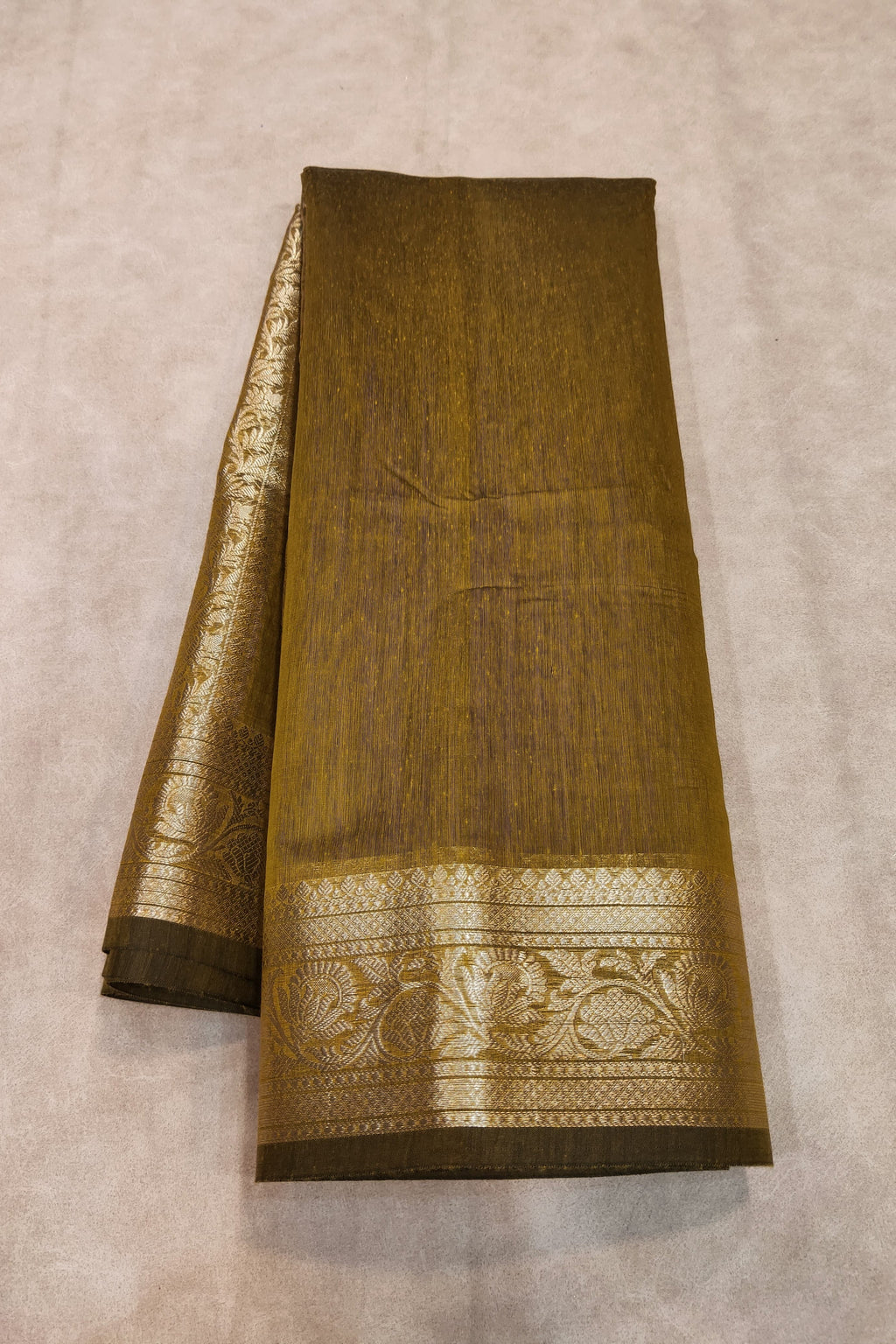 Brown saree with gold border on a beige background