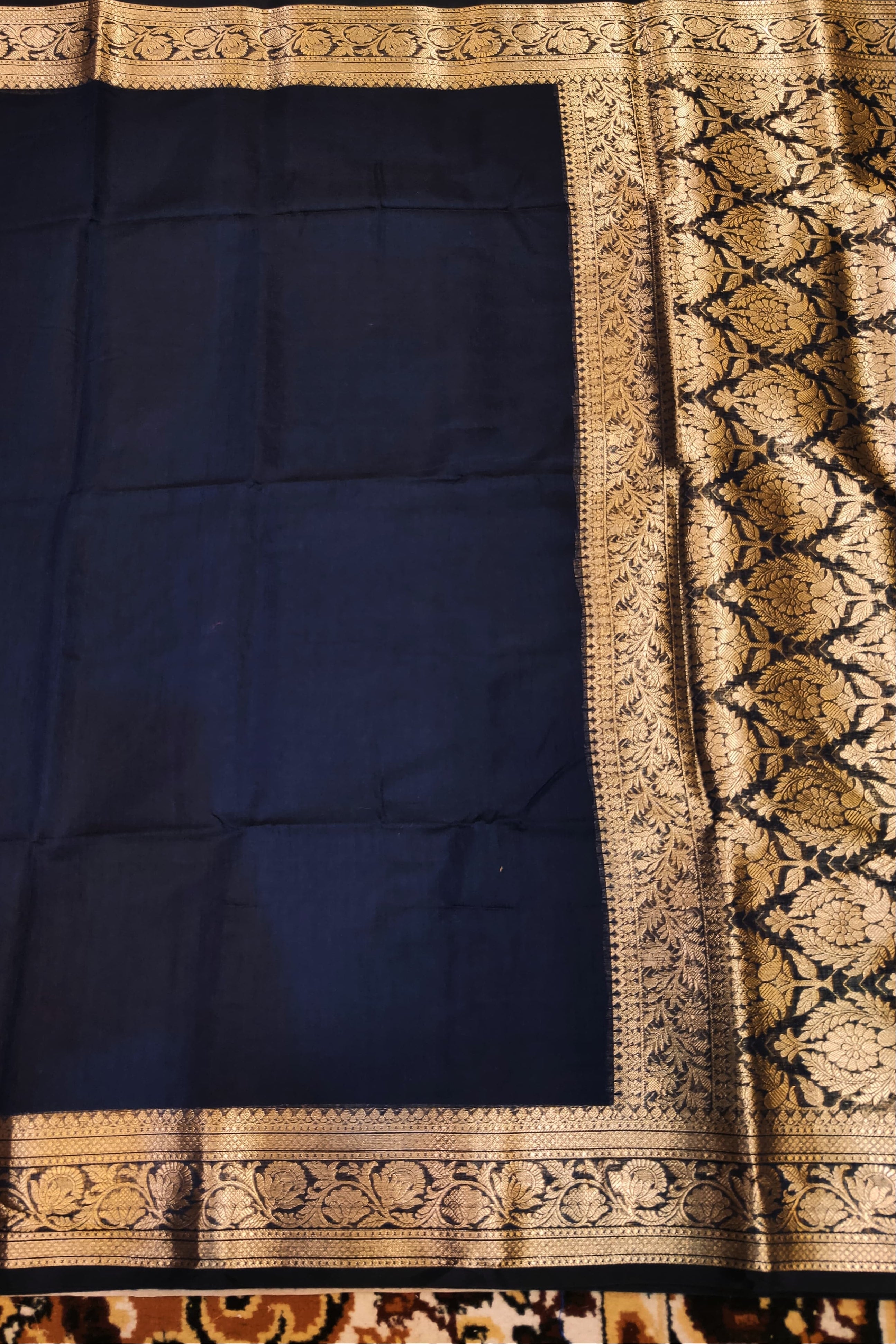 Navy blue fabric with gold embroidery on a patterned background