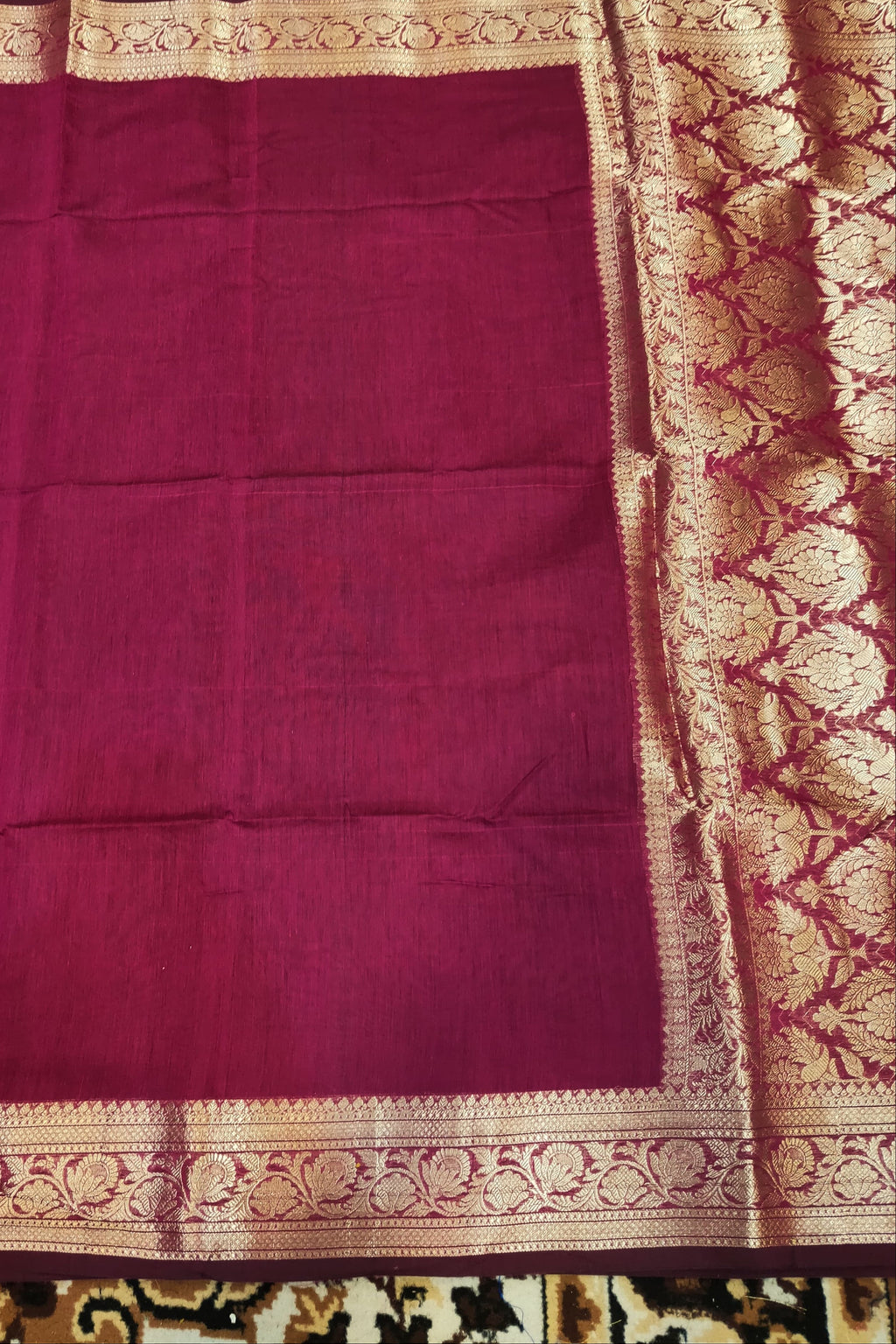 red saree with gold border on a patterned fabric background