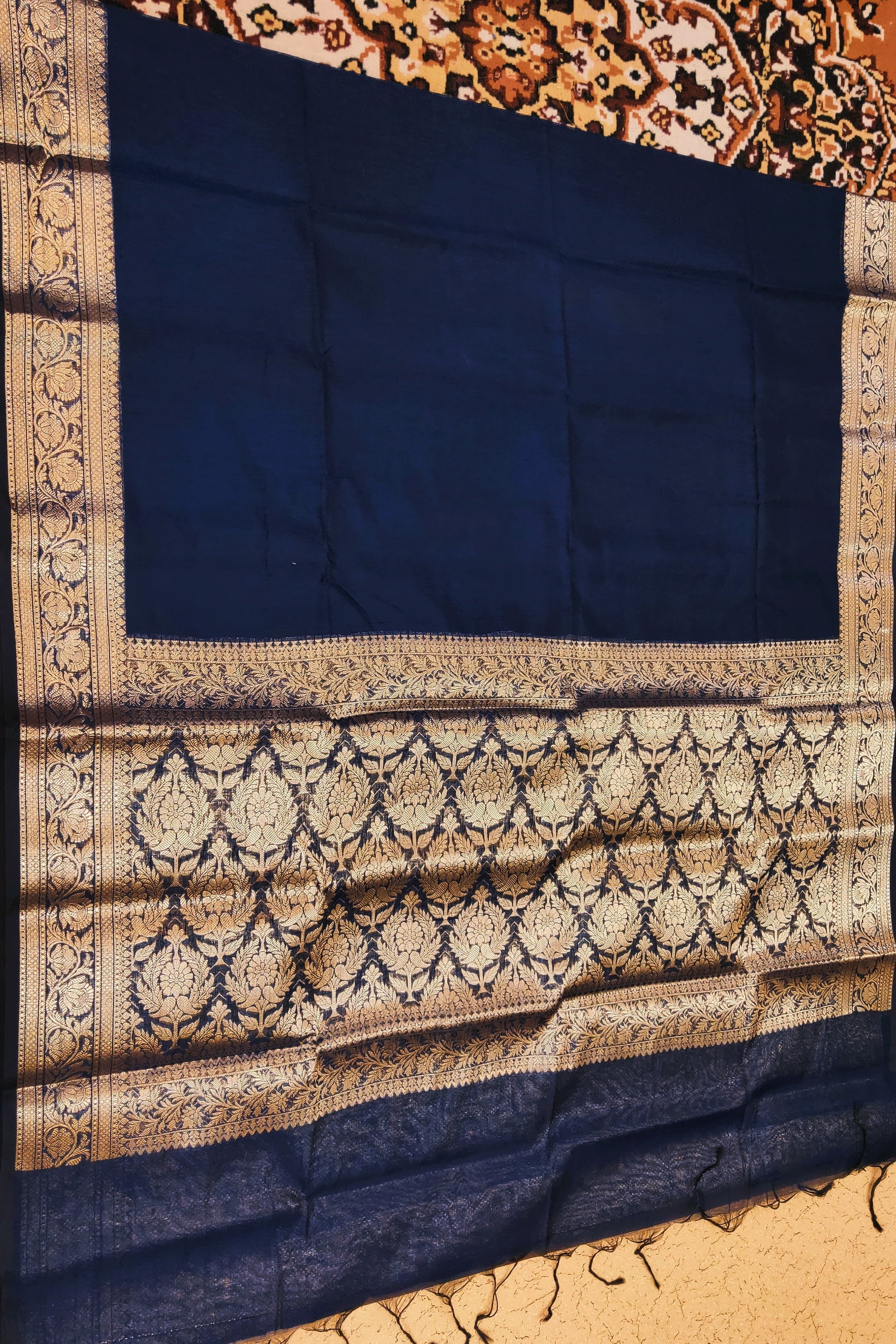 Navy blue fabric with intricate gold patterns on a textured surface