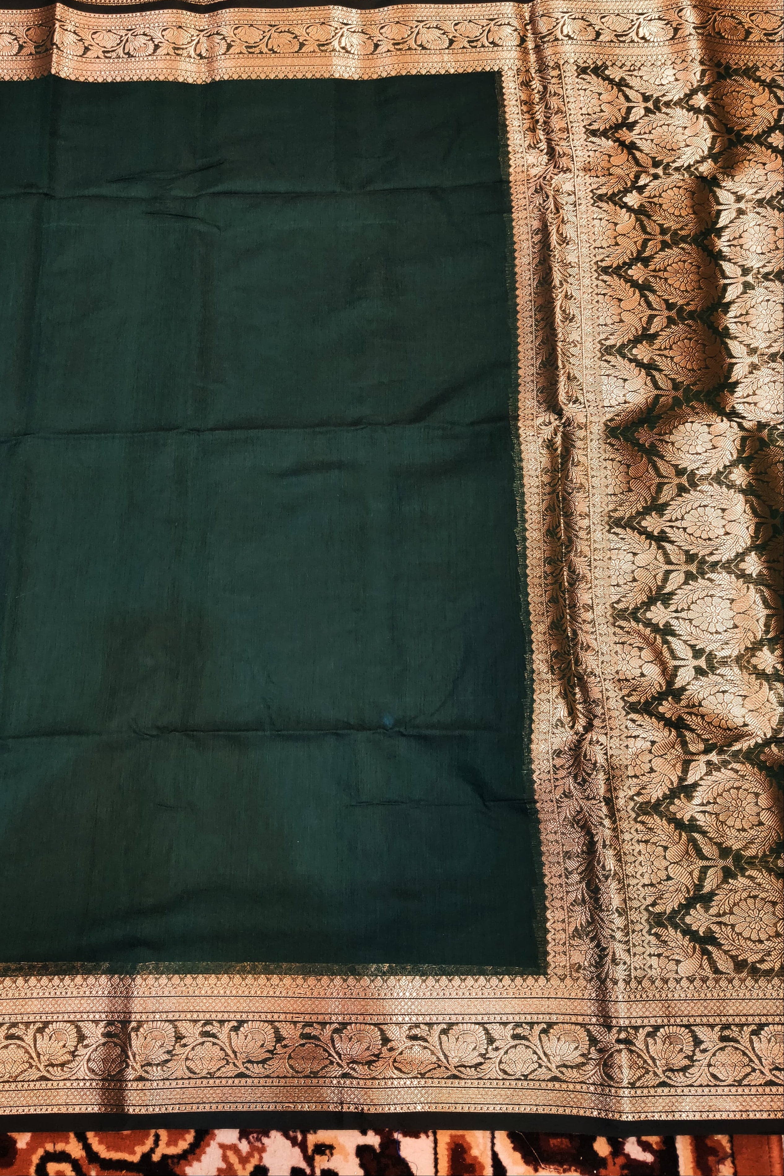 Dark green fabric with intricate gold border on a patterned background