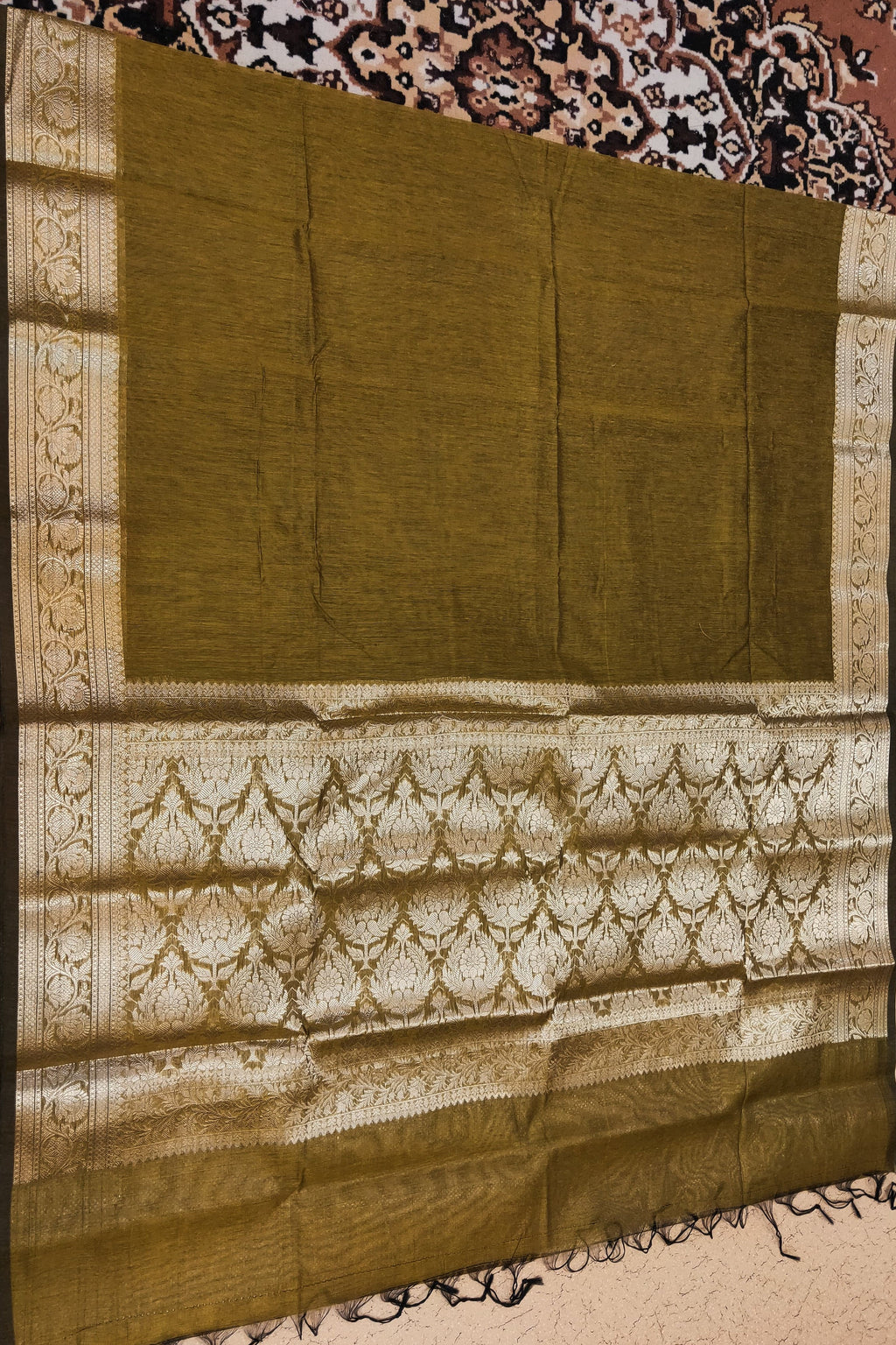 Green saree with white patterns on a patterned fabric background