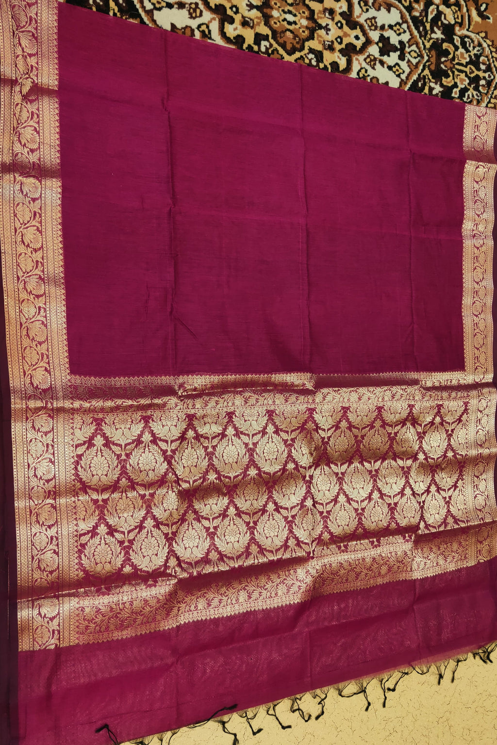 Purple saree with gold patterns on a decorative background