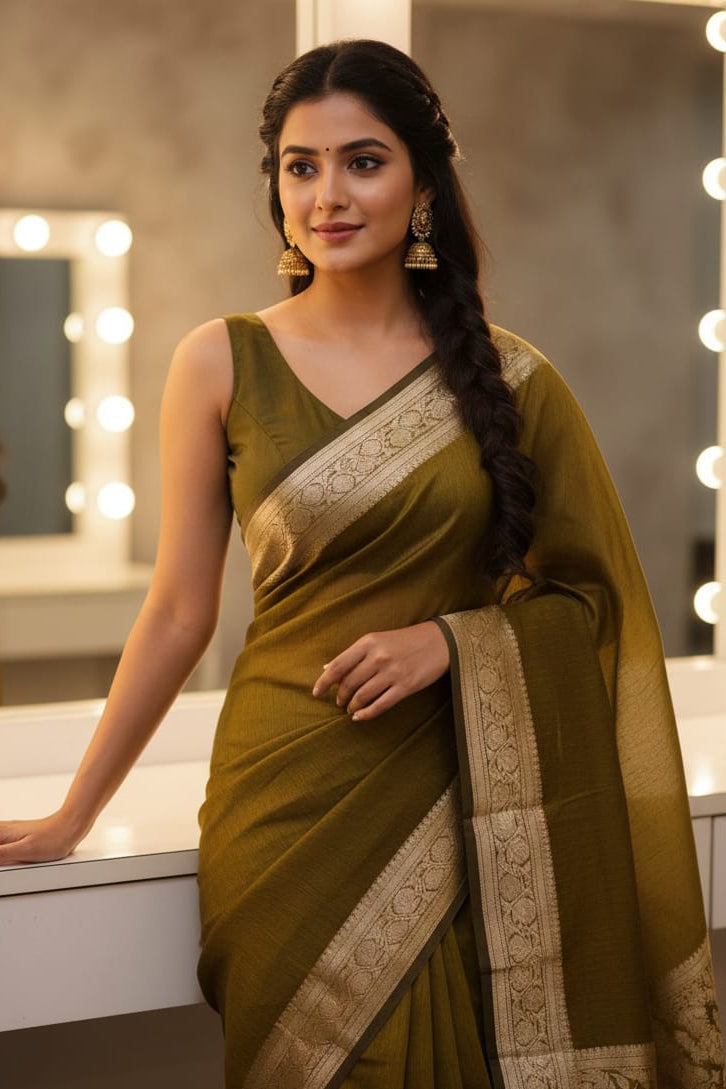 Woman in a green saree with white embroidery standing in front of a mirror with lights.