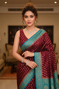 Woman in a maroon and blue saree with jewelry in an indoor setting