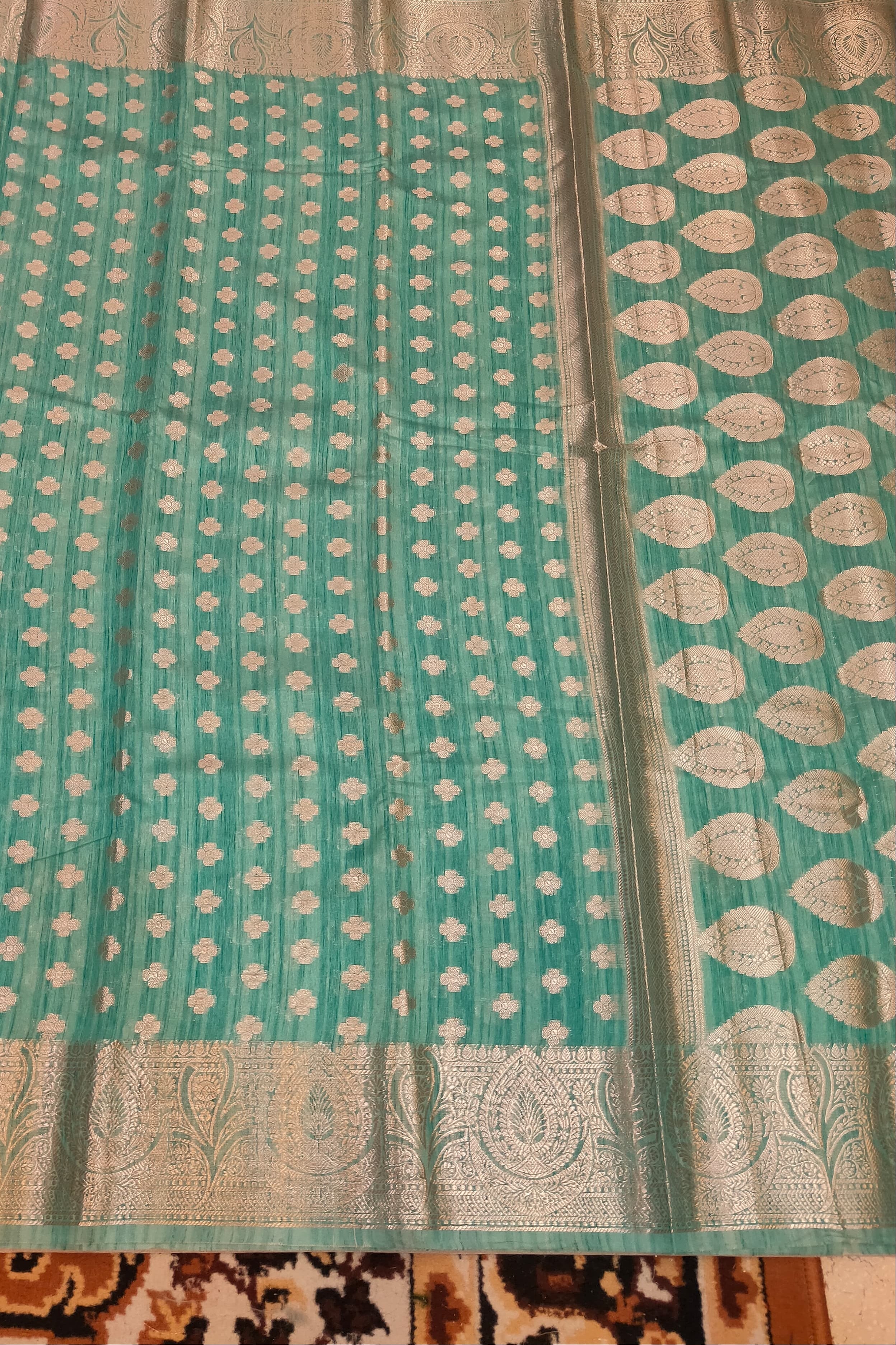 Teal fabric with white patterns on a patterned background