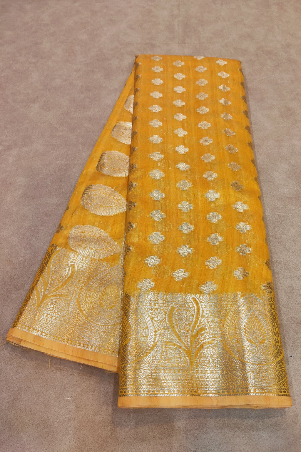Yellow fabric with gold patterns on a brown background