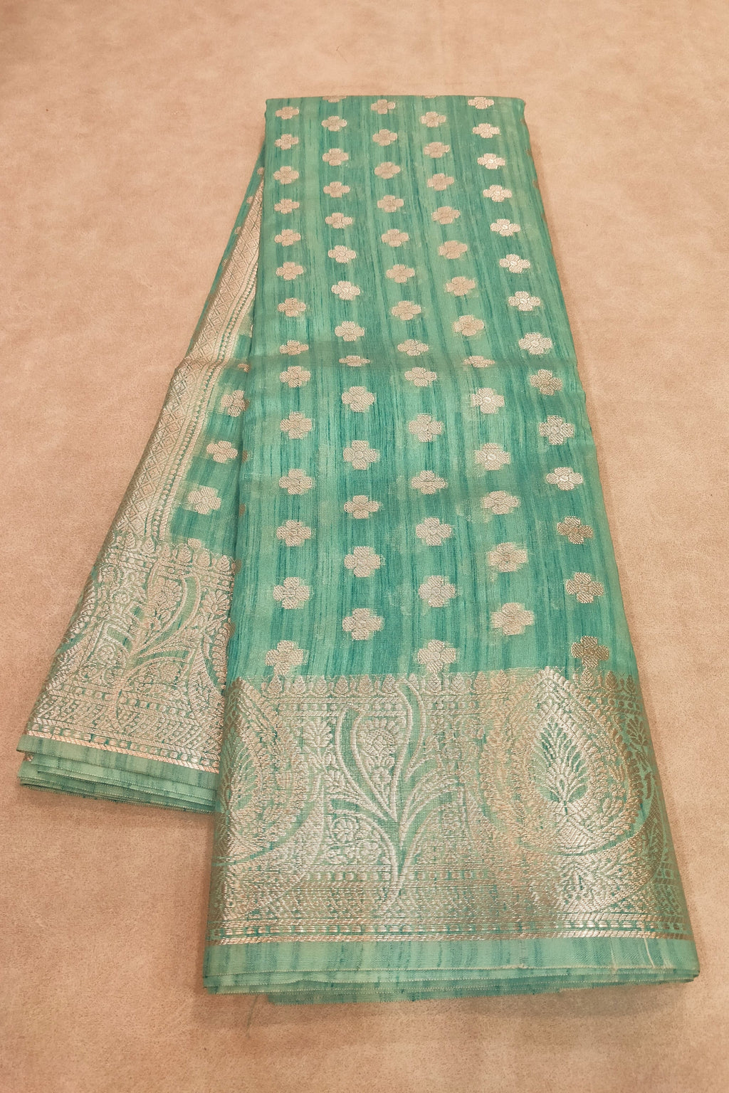 Green saree with white patterns on a beige background