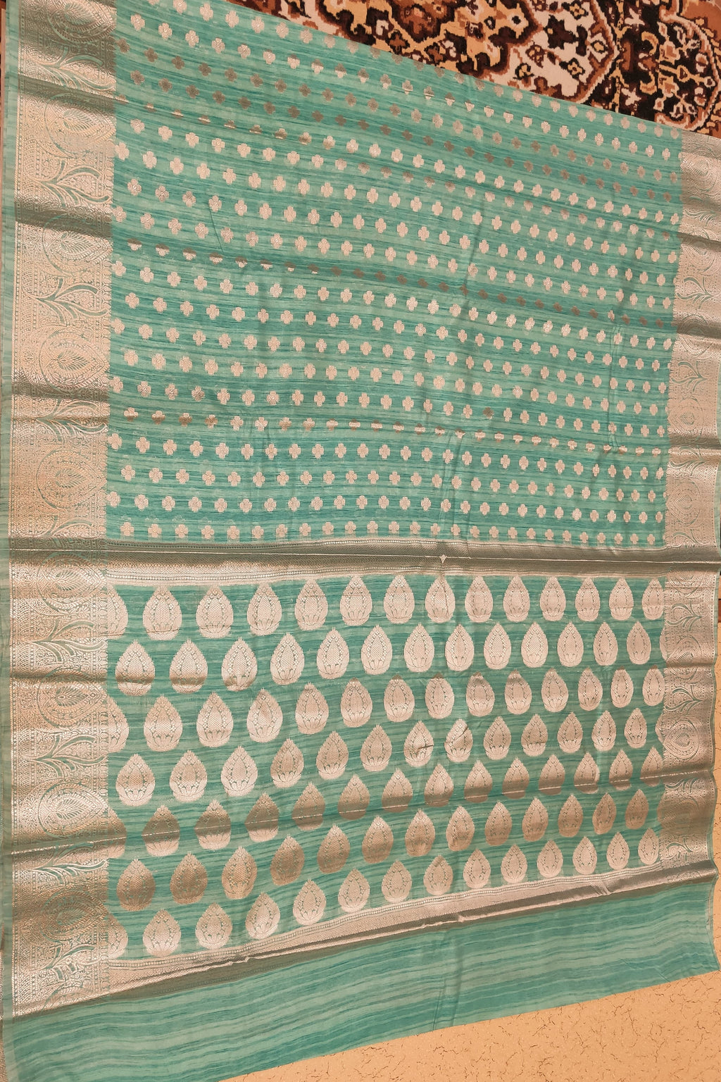 Teal and beige patterned fabric on a textured surface