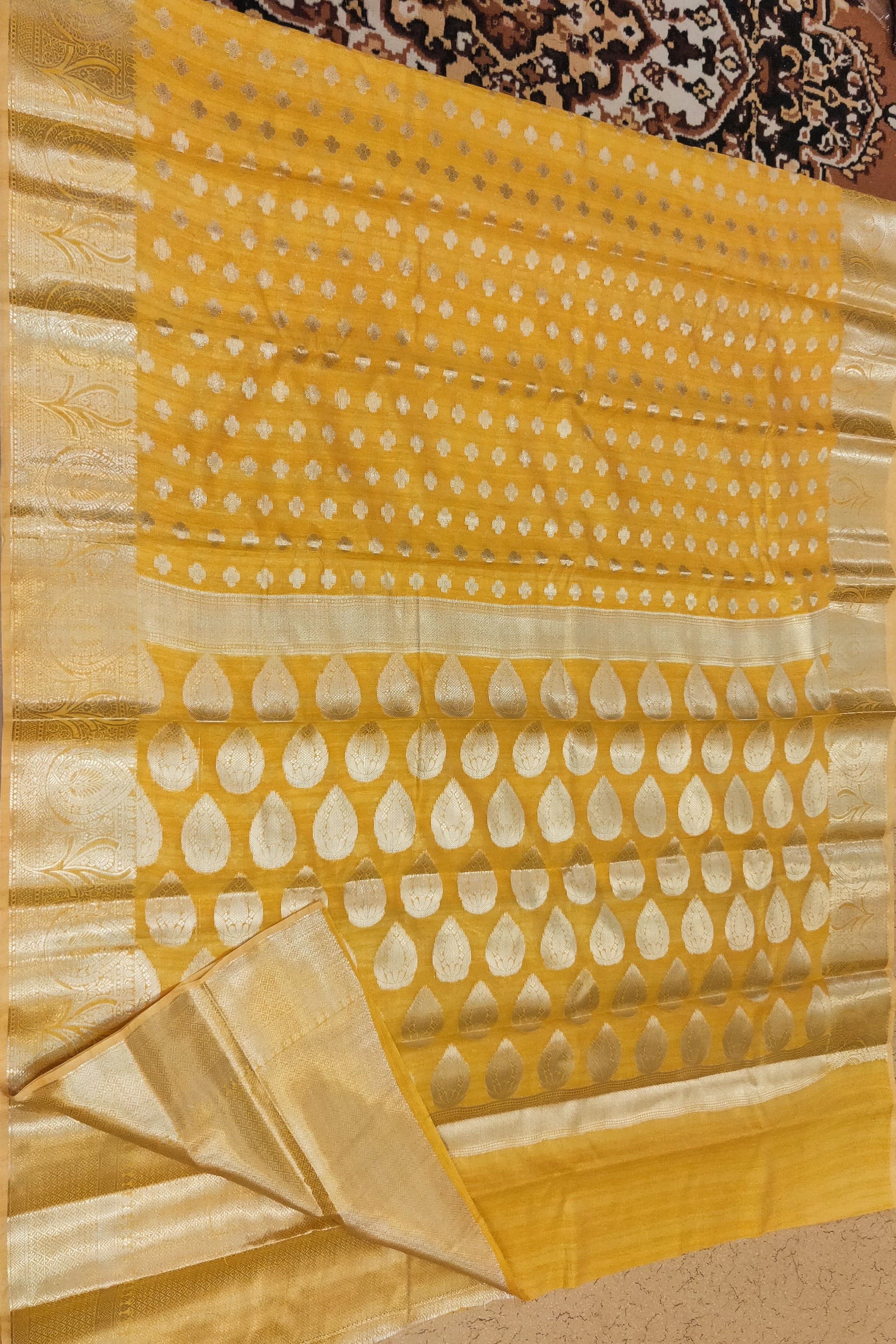 Yellow saree with white patterns on a patterned fabric background