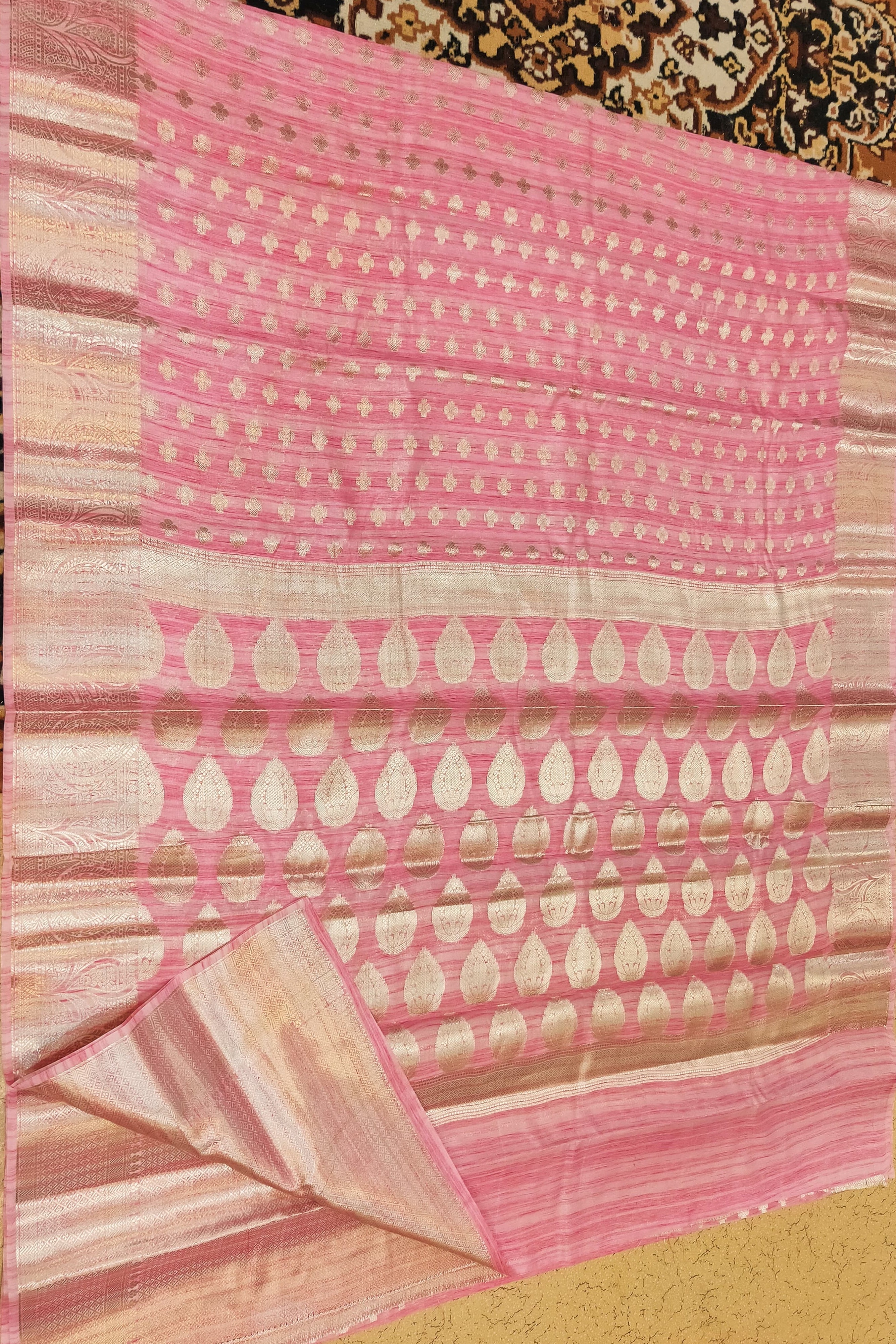 Pink and beige patterned fabric on a textured surface