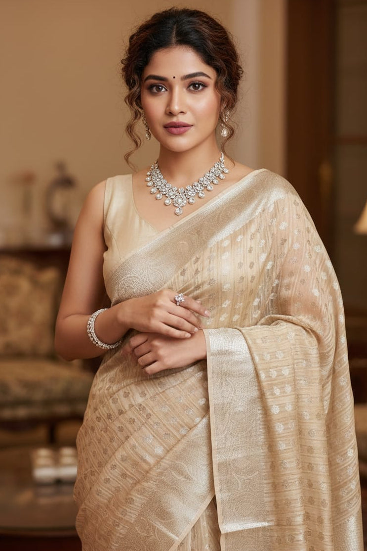 Woman in a beige saree with jewelry in an indoor setting