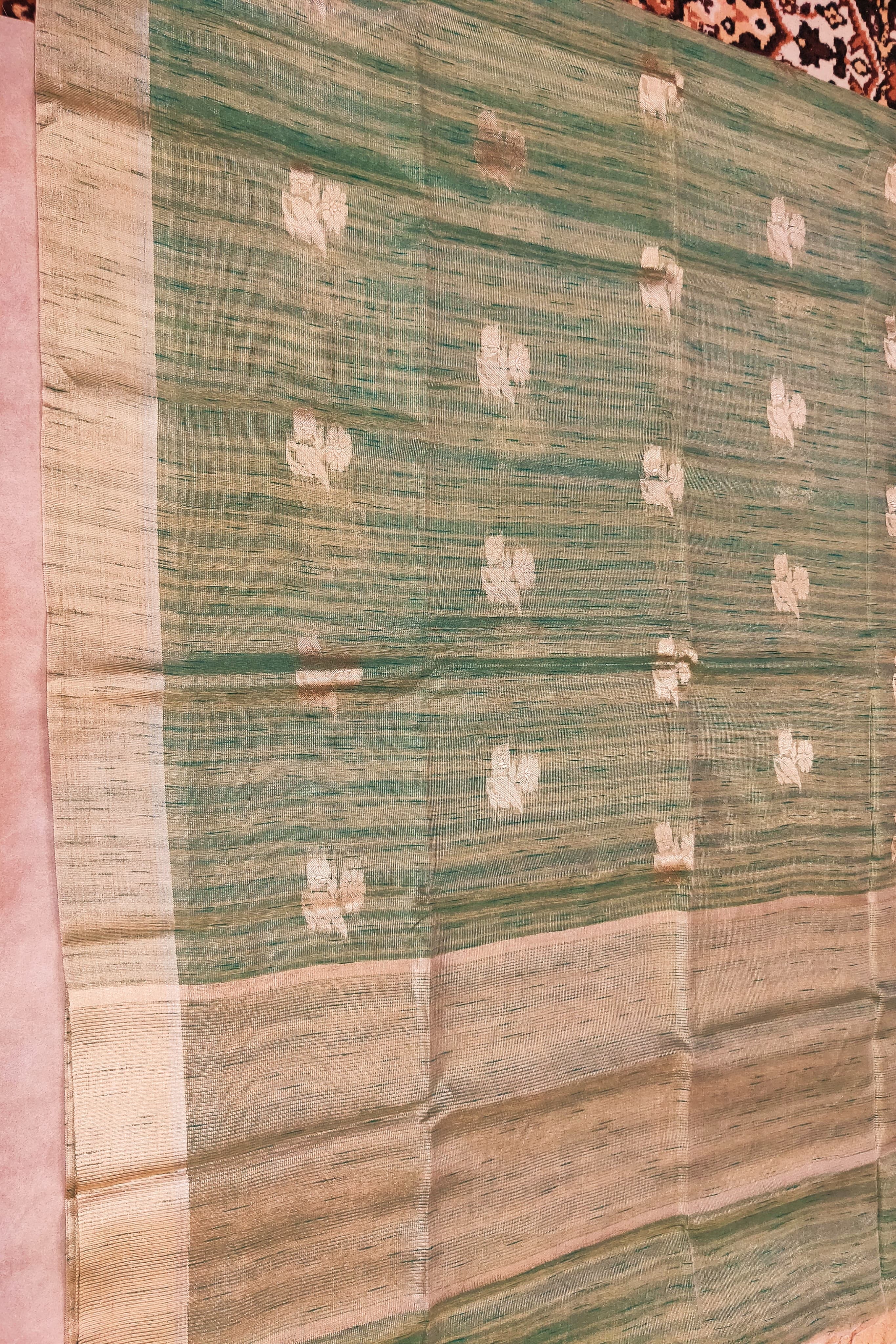 Green and beige patterned fabric on a wooden surface