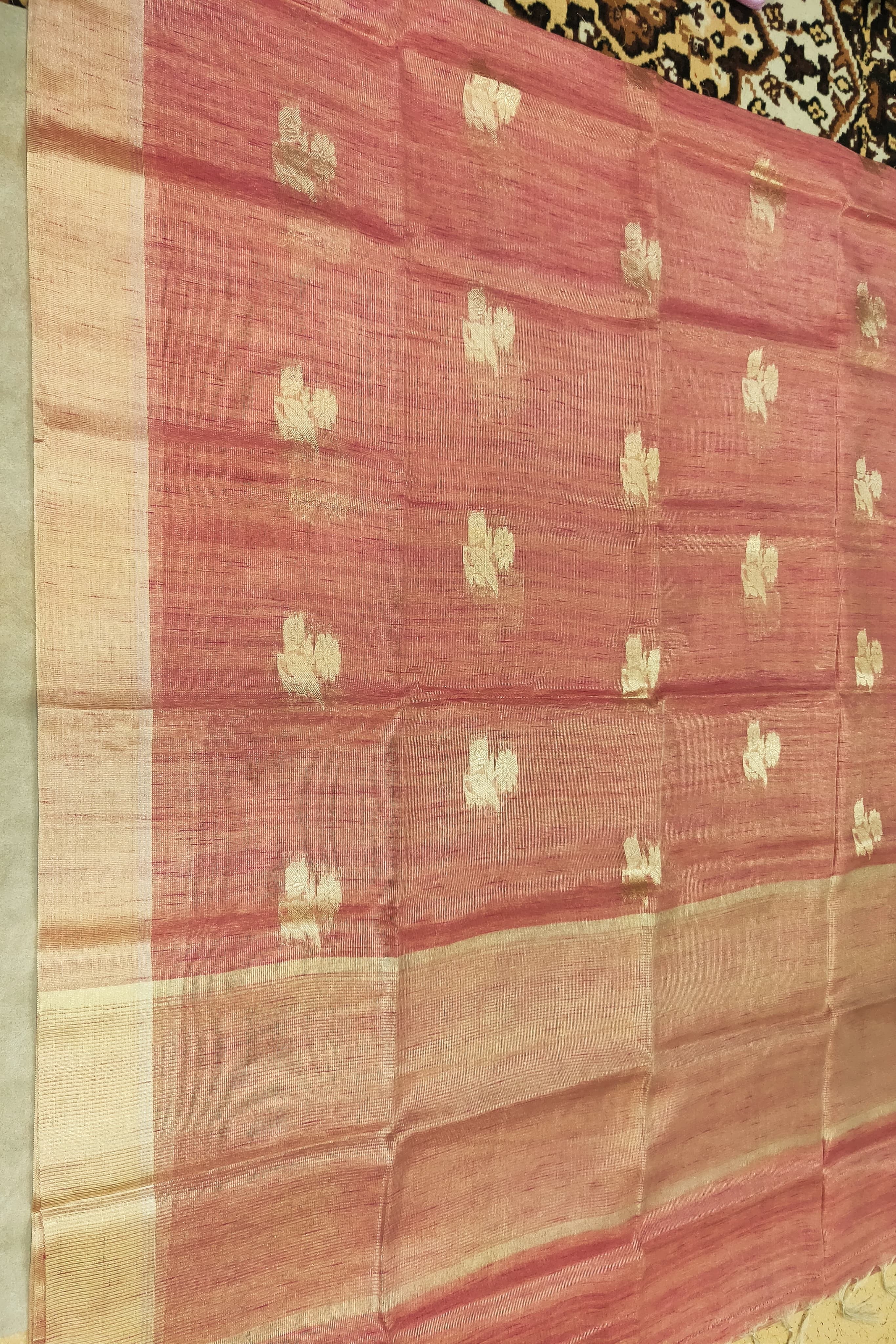 Red and beige fabric with gold patterns on a patterned background