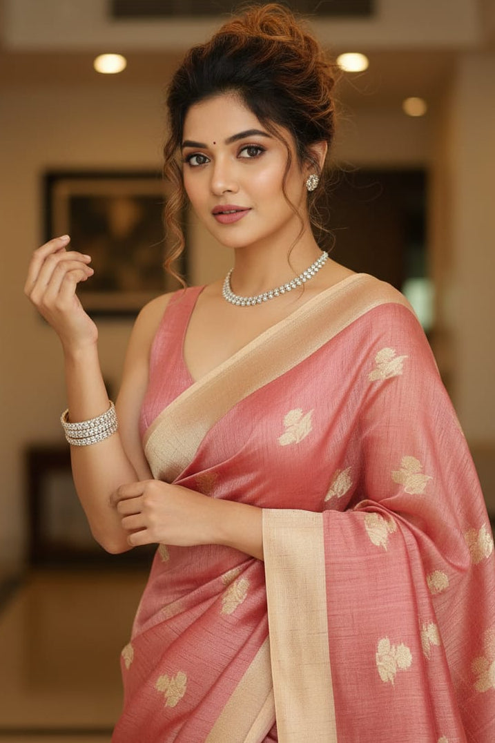 Woman in a pink saree with gold patterns indoors
