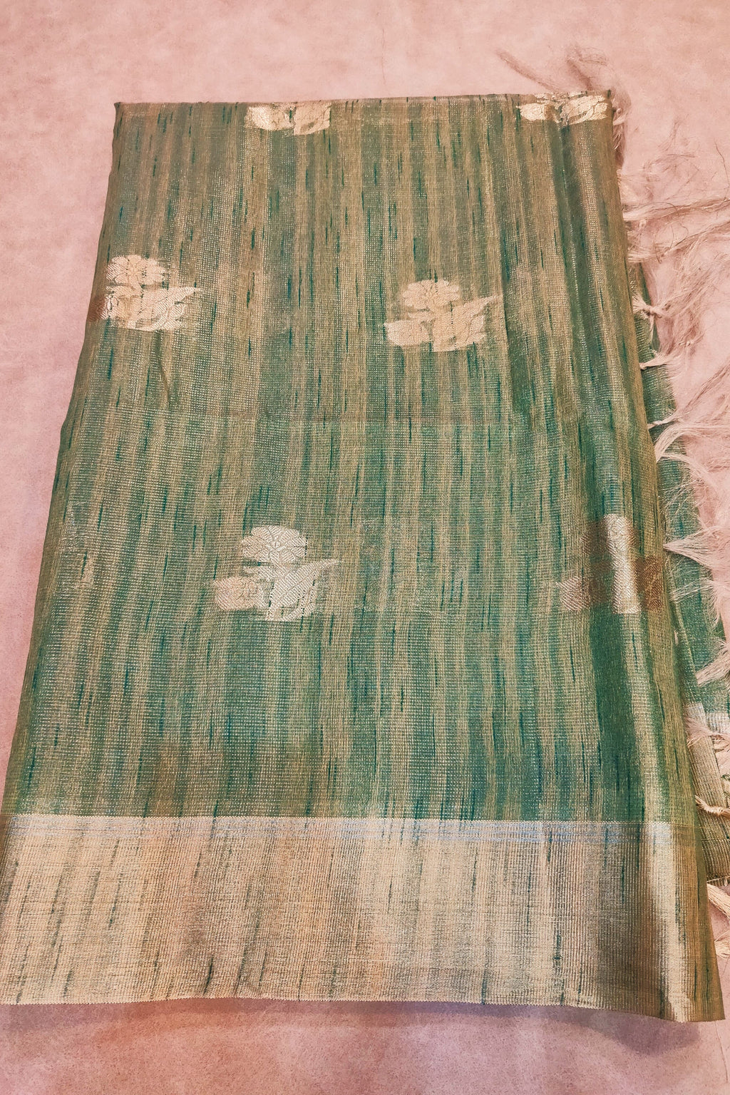 Green and beige patterned fabric on a pink background