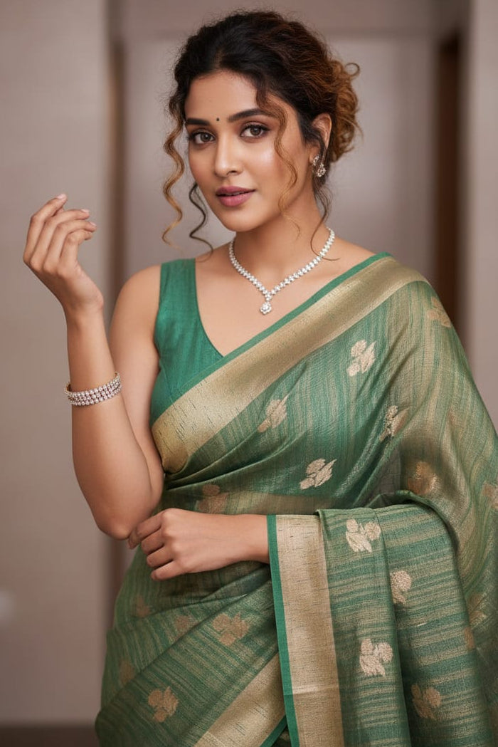 Woman wearing a green saree with a plain background