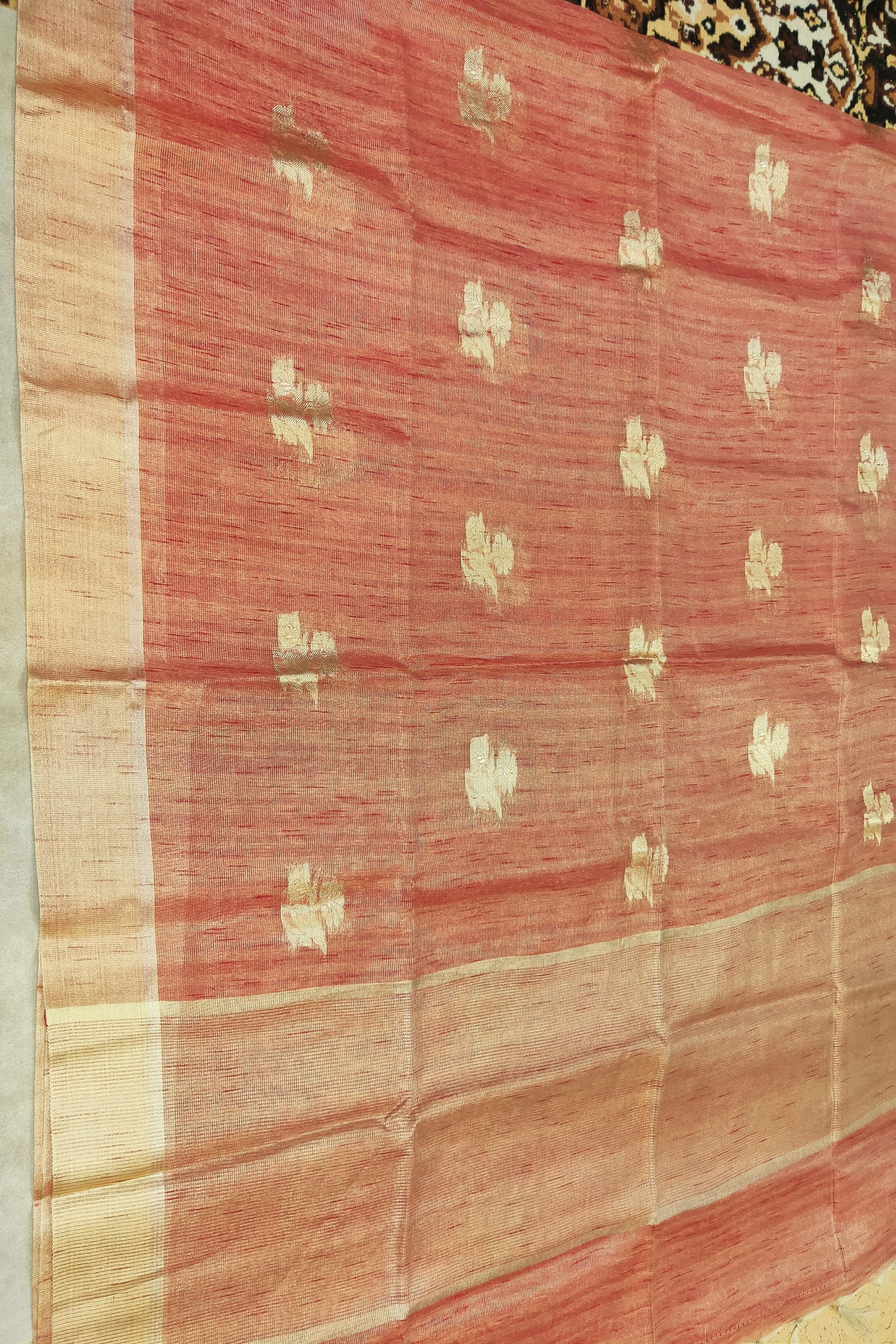 Red fabric with gold patterns on a wooden surface