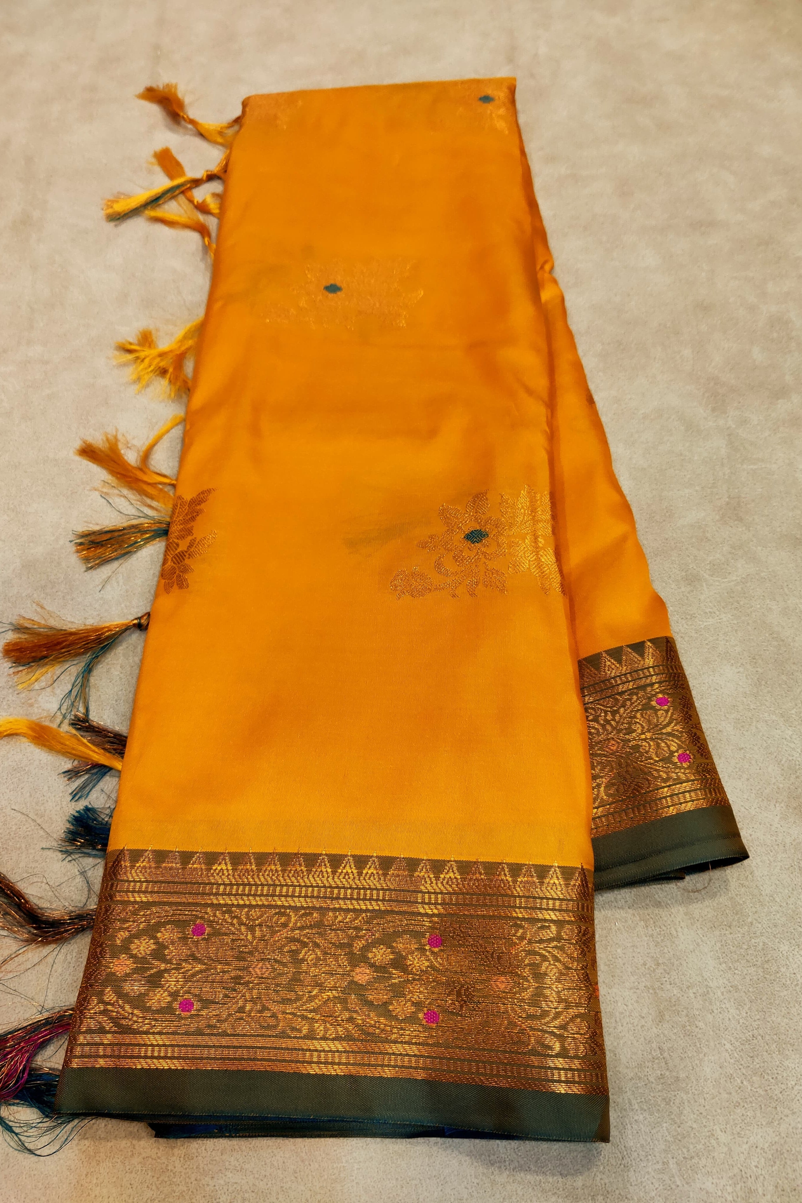 Yellow saree with a decorative border on a beige background